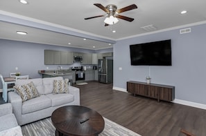 A modern living room with a grey sofa, a coffee table, and a ceiling fan.