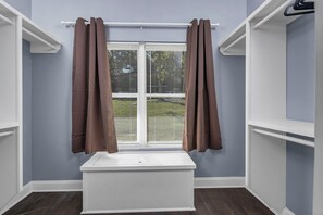 A room with a window, white built-in shelves, and a white bench.