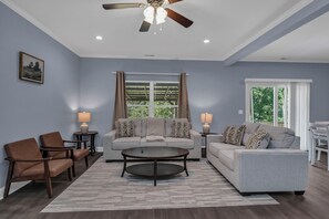 A living room with a ceiling fan, two sofas, a coffee table, and a painting on the wall.