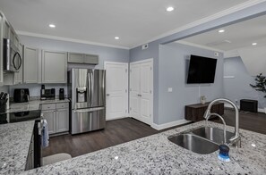 A modern kitchen with stainless steel appliances, a granite countertop, and a built-in dishwasher.