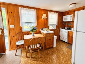 Eine kleine Küche mit Holzausstattung, einem Herd, einer Mikrowelle und einem Kühlschrank.