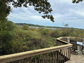 A wooden deck with a table and chairs overlooking a lake. - The Hidden Bungalow sleeps 4, has  AC & internet on Wabasis Lake in GreenvilleMI (Greenville)