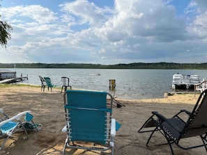 A lakeside view with a dock, chairs, and a boat. - The Hidden Bungalow sleeps 4, has  AC & internet on Wabasis Lake in GreenvilleMI (Greenville)