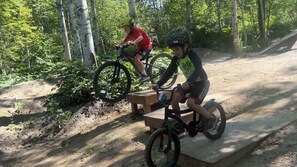 Two individuals on bicycles on a dirt path in a wooded area.