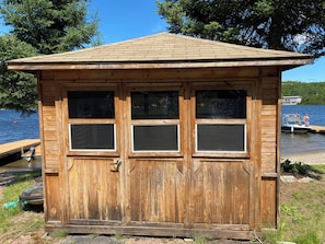 Eine Holzhütte mit Satteldach, drei Fenstern und einer Tür.