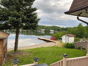 A lakeside property with a dock, a small shed, and a red bench.