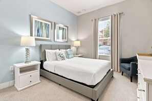 A bedroom with a bed, two bedside tables, a chair, a desk, and two framed pictures on the wall. - 12 Min to Disney, Mickey & Minions Themed Rooms (Kissimmee)