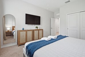 Ein Hotelzimmer mit Bett, Wandfernseher, Kleiderschrank und Tür.