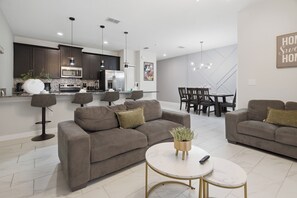 Ein modernes Wohnzimmer mit einer Couch, einem Couchtisch und einem Essbereich mit Stühlen und Tisch.