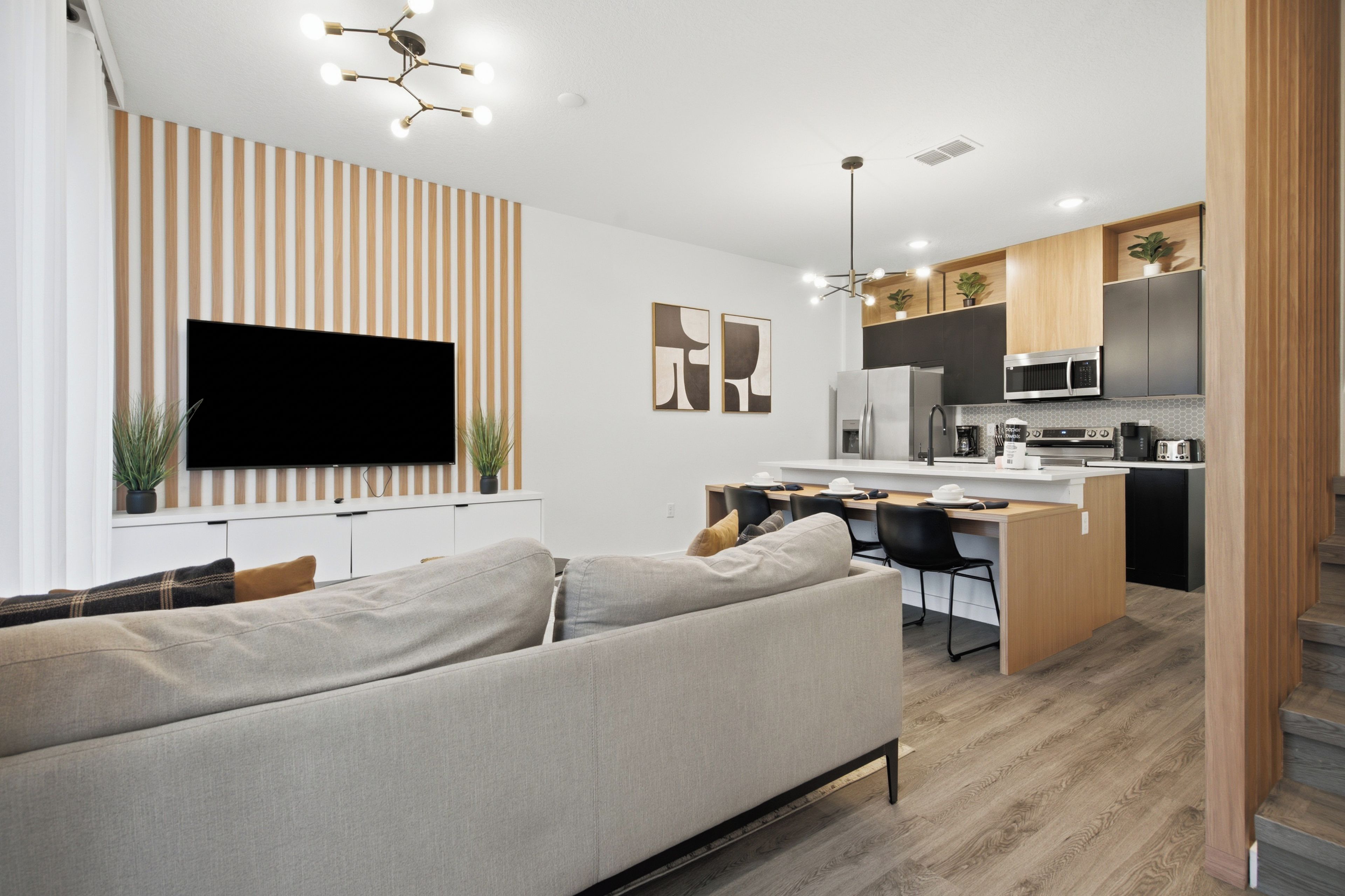 Eine moderne Küche mit Flachbildfernseher, Holzschränken und einem Essbereich mit einer Couch und Stühlen.