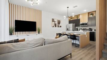 Eine moderne Küche mit Flachbildfernseher, Holzschränken und einem Essbereich mit einer Couch und Stühlen.