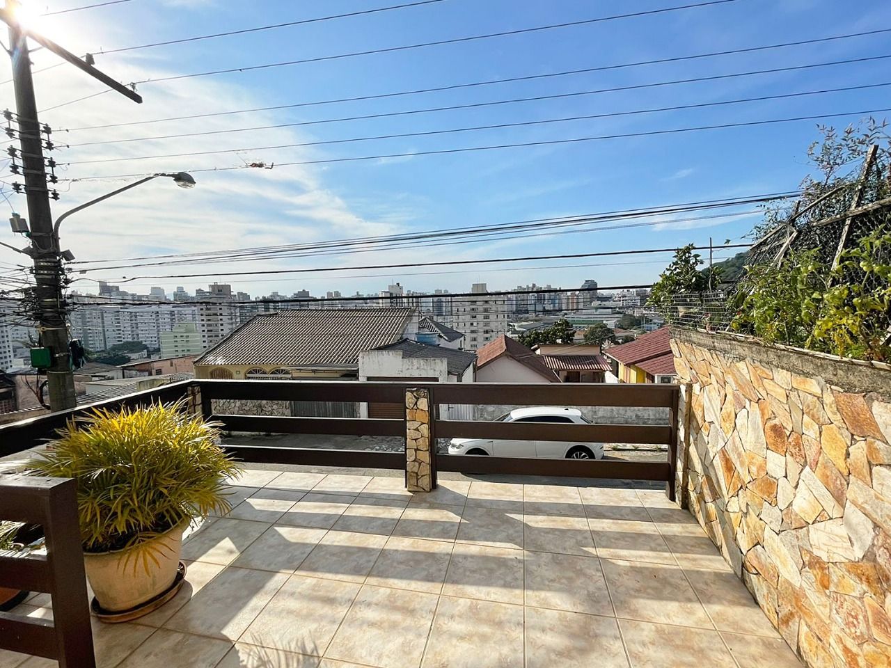 Terraço no telhado com parede de pedra, cerca de madeira e planta em vaso.