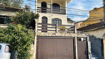 Una casa de dos pisos con fachada de piedra, un balcón y una entrada protegida por una reja.