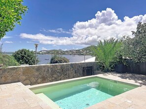 A swimming pool with a stone wall and a view of the sea. - Villa Les Alizés – Pinel Island View, Private Pool (Marigot)
