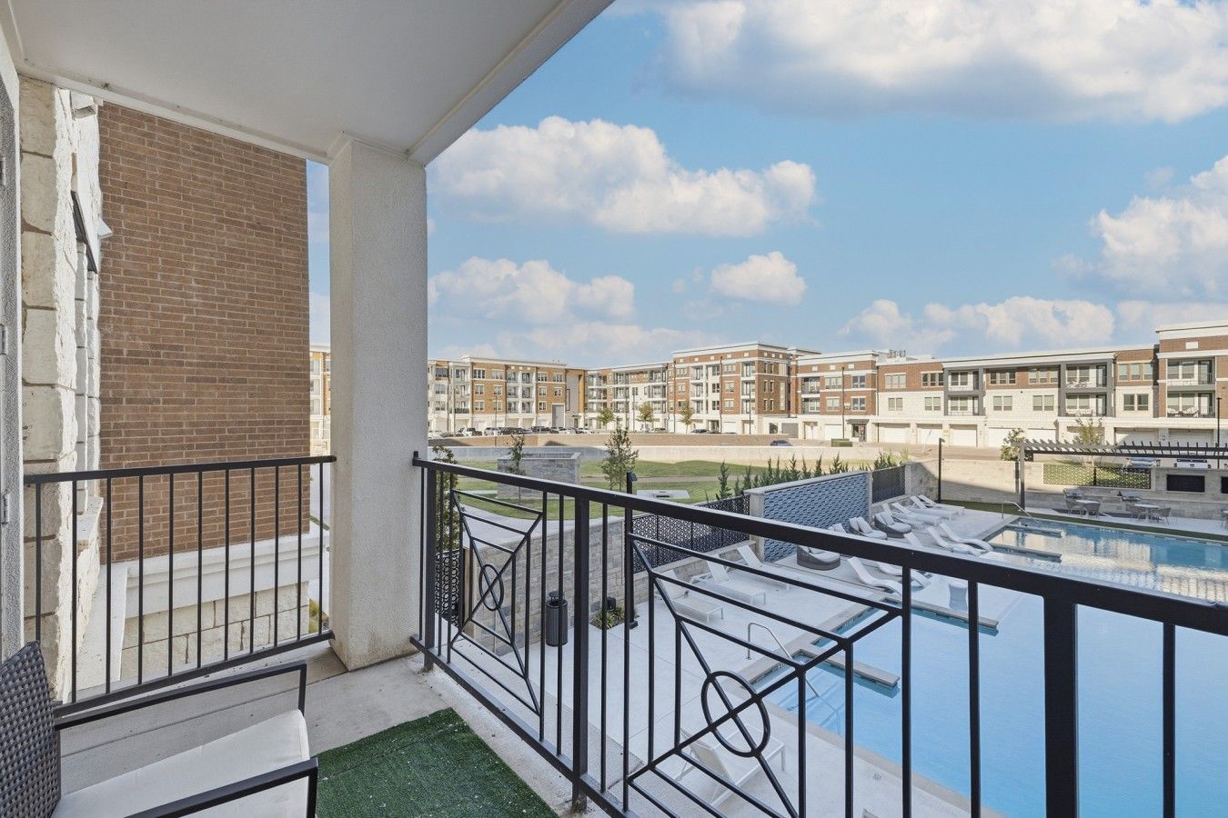 Ein Balkon mit Blick auf einen Swimmingpool und Apartmenthäuser im Hintergrund.