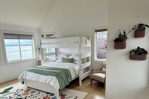 Ein Schlafraum mit Etagenbetten und Blick aufs Meer, einem kleinen Schreibtisch und einem Stuhl.