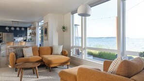 Un salon moderne avec un ensemble de canapés, une table basse et une vue sur un plan d’eau.