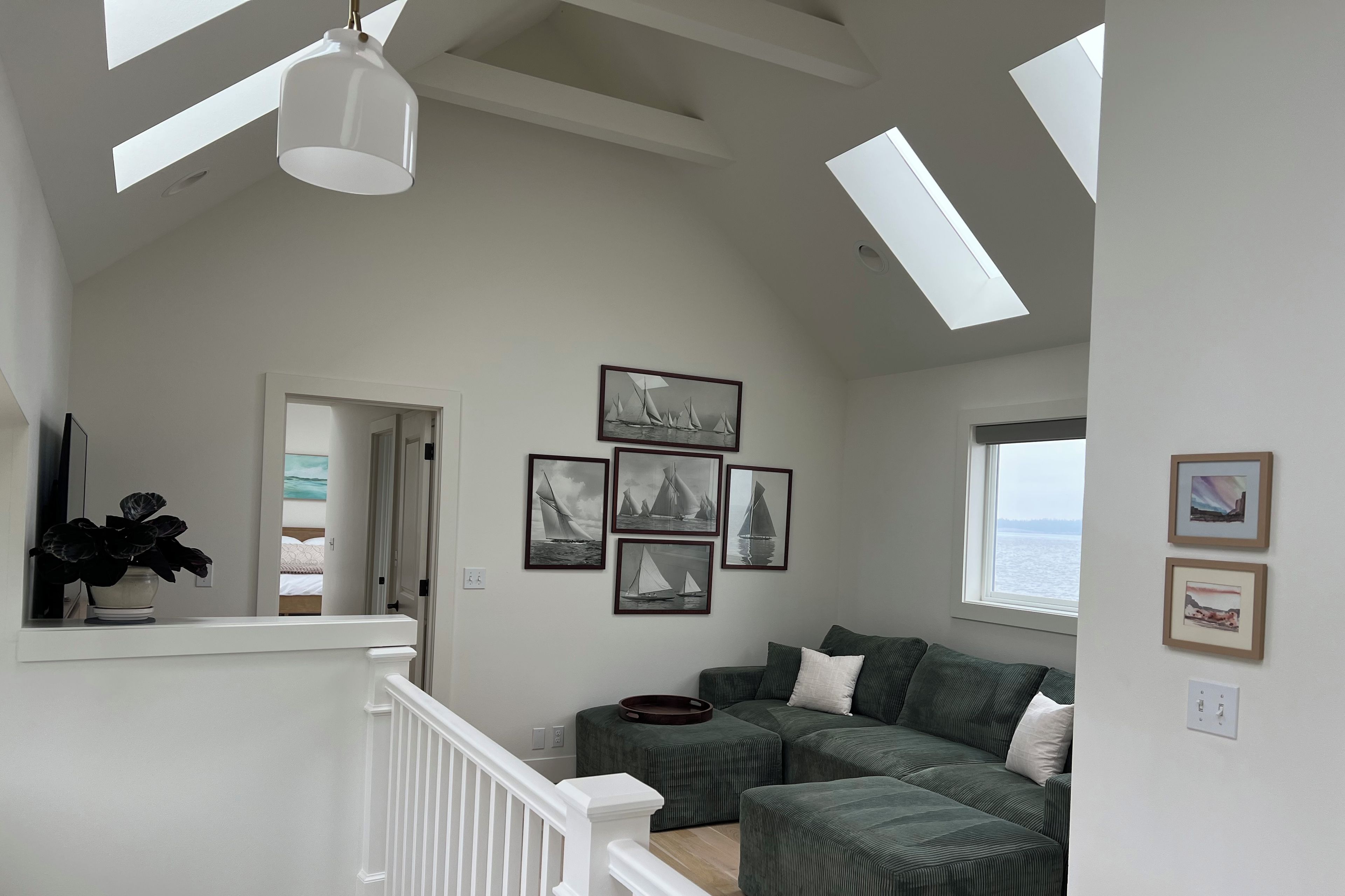 A spacious room with a high ceiling, a green sofa, a white railing, and a skylight.