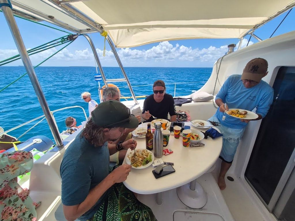 Eine Gruppe von Menschen speist auf einem Boot mit Blick auf den Ozean.