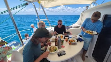 Eine Gruppe von Menschen speist auf einem Boot mit Blick auf den Ozean.