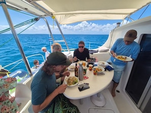 A group of people dining on a boat with a view of the ocean.