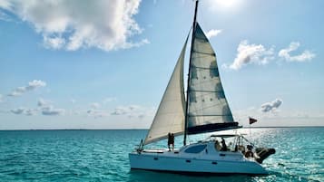 Un velero con un solo mástil y una persona de pie en la popa.