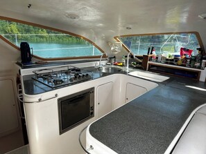 A compact kitchen with a gas stove, sink, and a window overlooking a body of water.