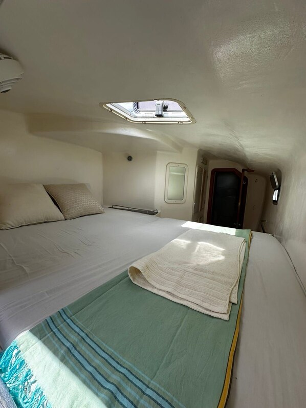 A compact bedroom with a single bed, a window, and a small skylight.