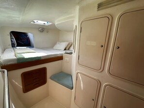A compact cabin with a bunk bed, a small seating area, and storage cabinets.