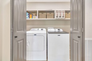 A laundry room with two Maytag washing machines and storage shelves above. - Charming 3-bedroom lakehouse in Hartwell with plenty of outdoor living space (Hartwell)