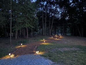 Ein bewaldetes Gebiet mit einem Kiesweg und gleichmäßig verteilten Leuchten.