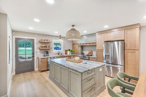 A modern kitchen with a large island, stainless steel appliances, and a view of the outdoors. - Charming 3-bedroom lakehouse in Hartwell with plenty of outdoor living space (Hartwell)