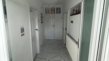 A hallway with white walls, a tiled floor, and a door at the end.