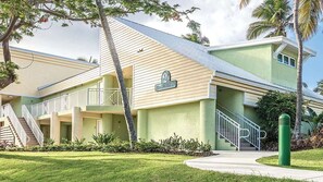 Un hôtel de deux étages, à la façade vert clair, doté d’un espace extérieur couvert avec un escalier, et d’une enseigne indiquant son nom.