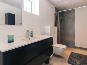 Une salle de bain moderne avec un lavabo blanc, un meuble-lavabo noir, des toilettes et un espace douche.