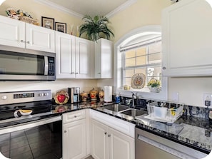 A kitchen with white cabinets, a microwave, an oven, a sink, and a window with a view. - Sunny Golf Course Condo Pool - 8 Min. To Beach! With AC (Myrtle Beach)