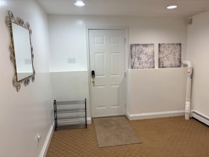 A hallway with a white door, a metal-framed mirror, a black rack, and a patterned rug. - Beautiful 2-bedroom apartment in welcoming Newton neighborhood (Newton)