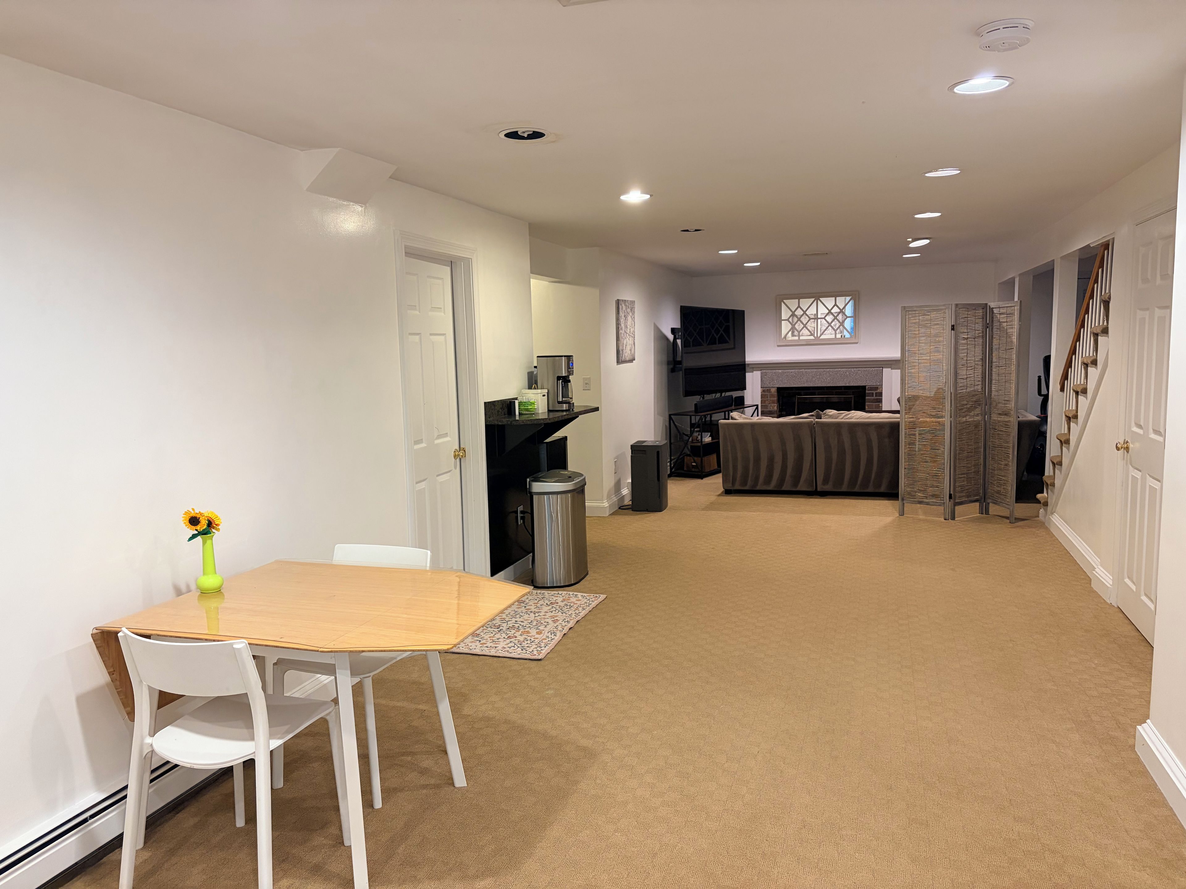 A modern kitchen with a built-in oven, a dining area with a table and chairs, and a living room with a sofa and a fireplace.