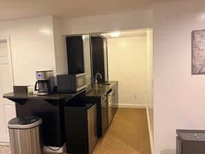 A compact kitchen with a coffee maker, microwave, and refrigerator.