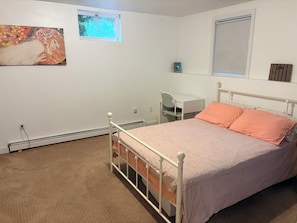 A bedroom with a bed, a desk, and a chair. There is a window with a view of trees. - Beautiful 2-bedroom apartment in welcoming Newton neighborhood (Newton)