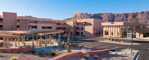 Un hotel de varios pisos con estacionamiento techado, asientos al aire libre y vistas a montañas.