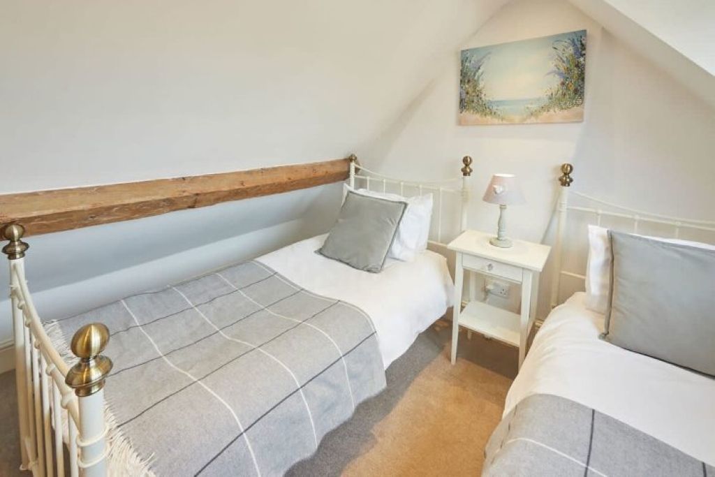A bedroom with two beds, a nightstand, and a painting on the wall.