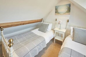 A bedroom with two beds, a nightstand, and a painting on the wall. - Rose Cottage - Pickering (Pickering)