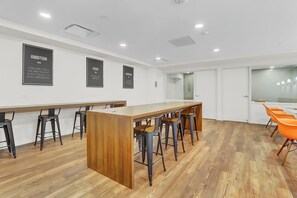 Ein moderner Konferenzraum mit einem langen Holztisch, schwarzen und orangefarbenen Stühlen und motivierenden Postern an den Wänden.