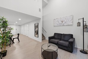 A modern living room with a grey sofa, a glass coffee table, and a painting on the wall. - PremiumStays: Modern : Central to sports, arena, Theater : Loft : Parking : Gym (Cleveland)