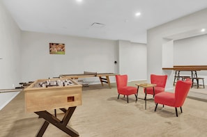 A room with a foosball table, two red chairs, and a small table with a wooden top. - PremiumStays: Modern : Central to sports, arena, Theater : Loft : Parking : Gym (Cleveland)