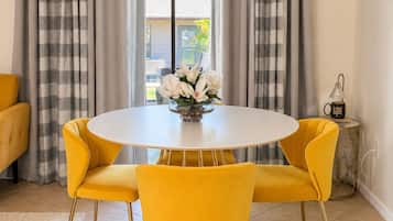 A dining area with a round table, yellow chairs, and a vase of flowers.