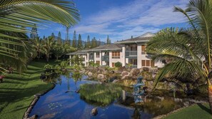 Een resort met een zwembad, palmbomen en een gebouw met meerdere balkons.