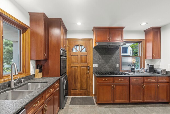 A kitchen with wooden cabinets, a stainless steel sink, a built-in oven, and a gas stove.