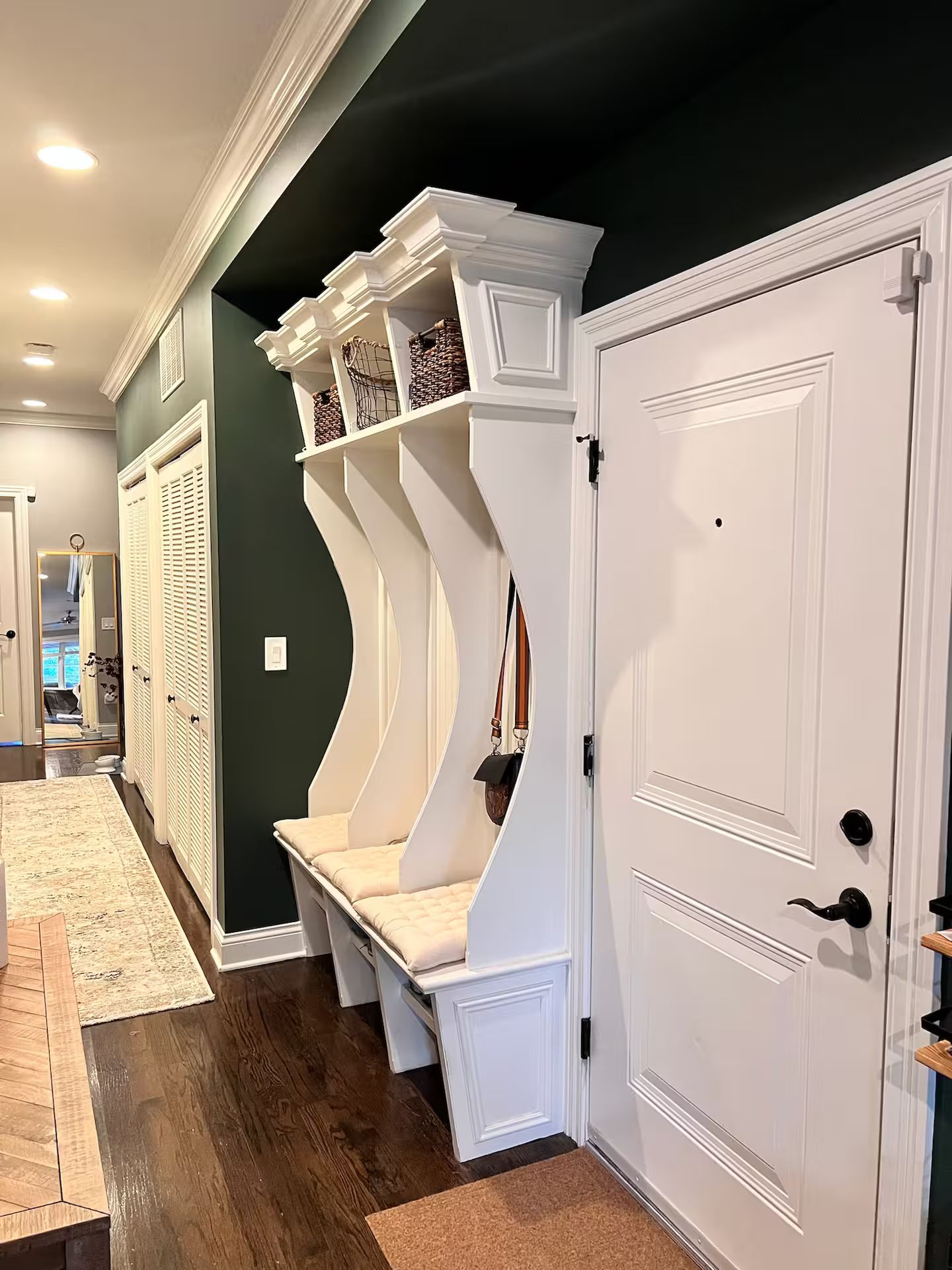 A hallway with a built-in bench, a door, and a mirror.